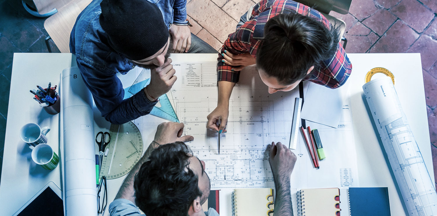 trio at a drafting table with blueprints